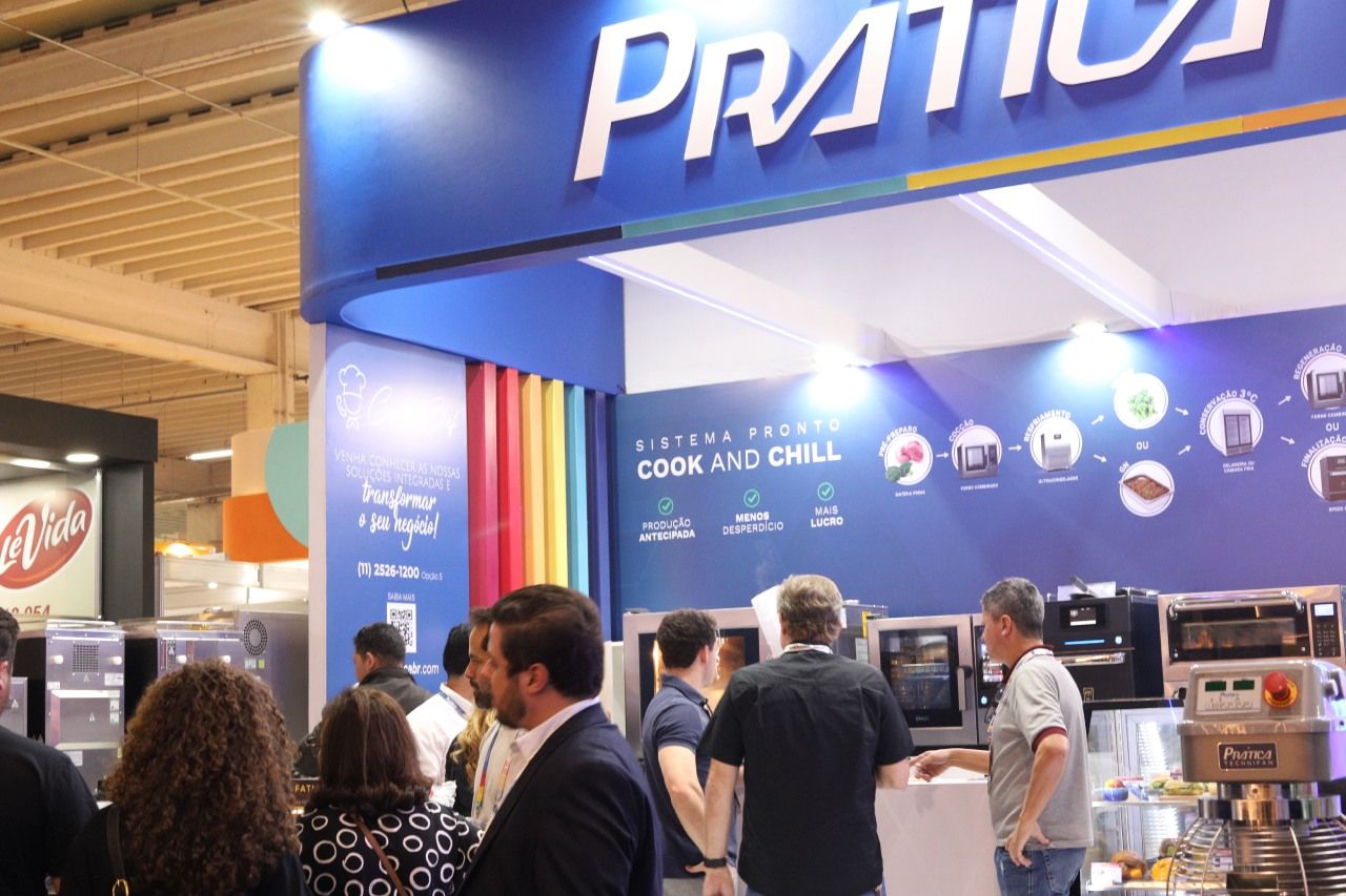 Um grupo de pessoas está em frente a um estande de pratika.