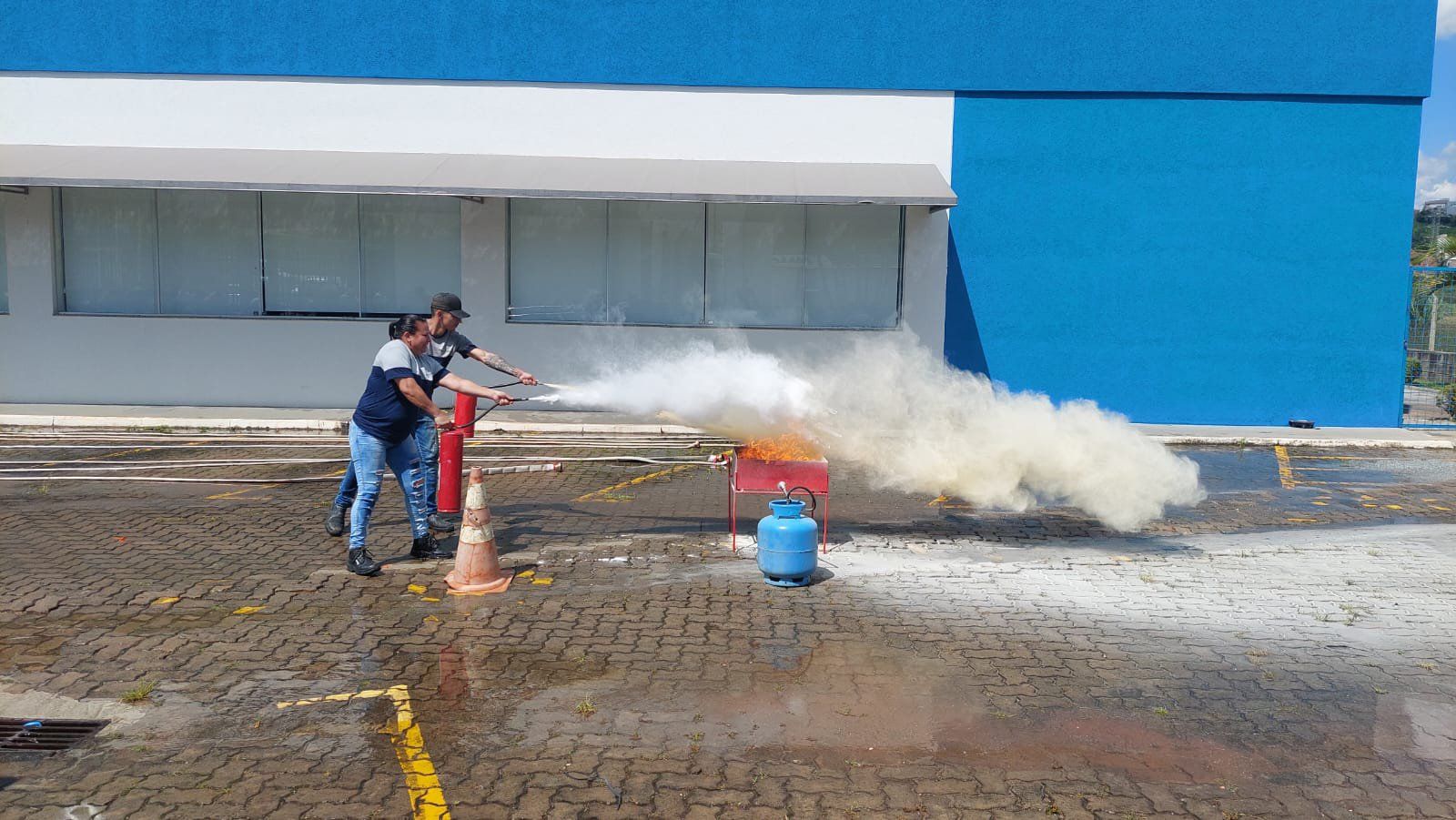 Um homem está usando um extintor de incêndio para apagar um incêndio em um estacionamento.