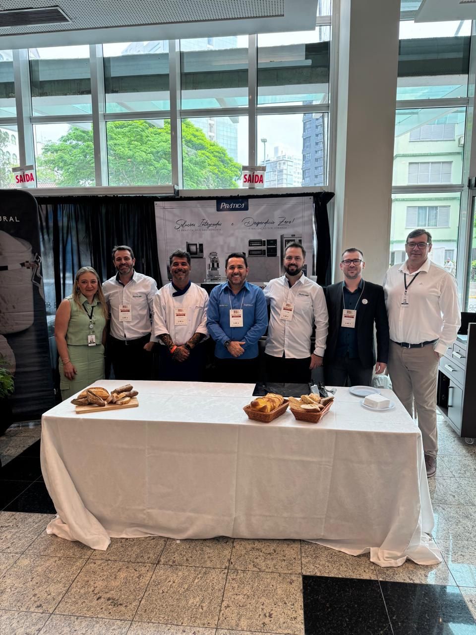 Um grupo de pessoas em pé ao redor de uma mesa com comida sobre ela