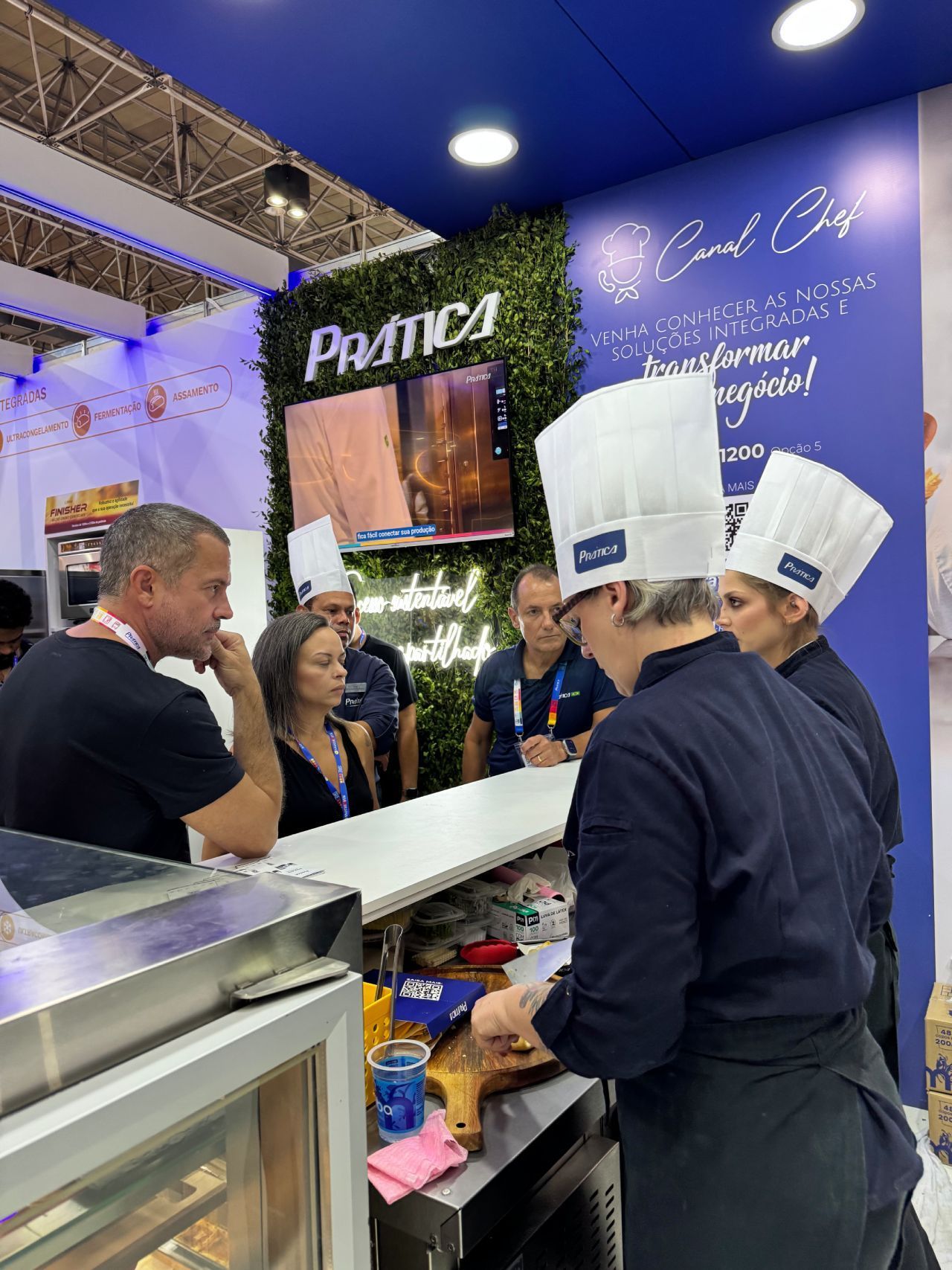 Um grupo de pessoas usando chapéus de chef estão em volta de um balcão.