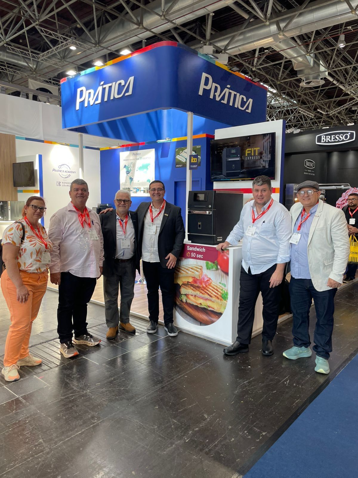 Um grupo de pessoas está posando para uma foto em frente a um estande em uma convenção.