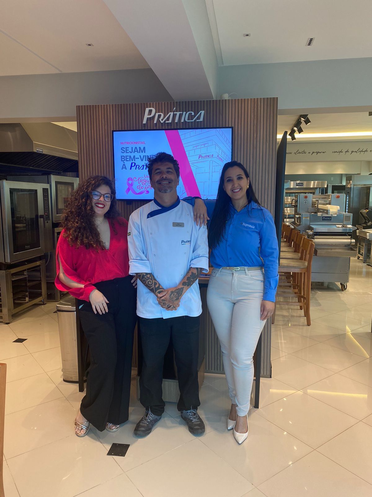 Um homem e duas mulheres estão posando para uma foto em uma cozinha.