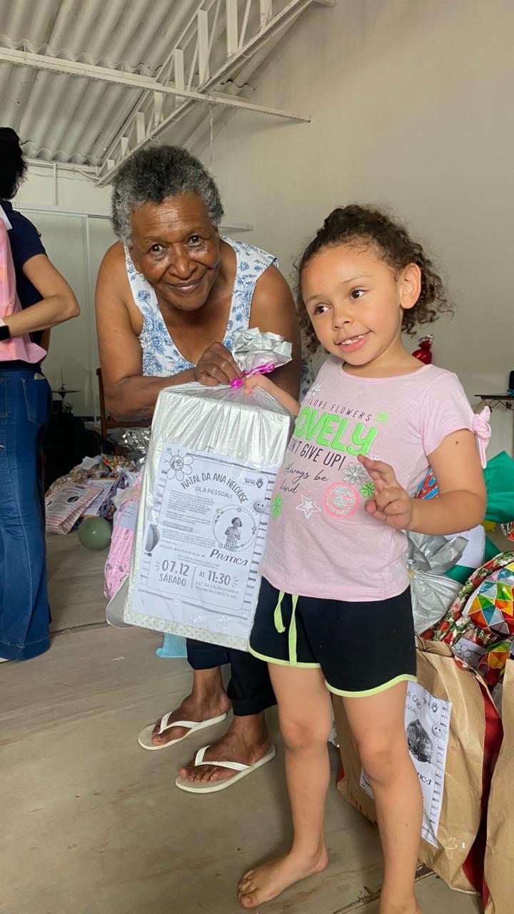 Uma mulher está parada ao lado de uma menina segurando uma caixa de presente.