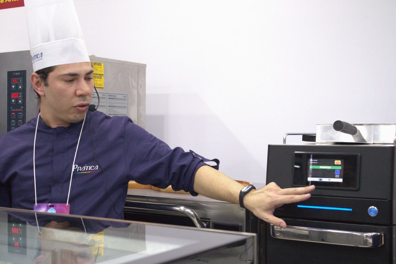 Um homem usando um chapéu de chef está parado em frente a um forno