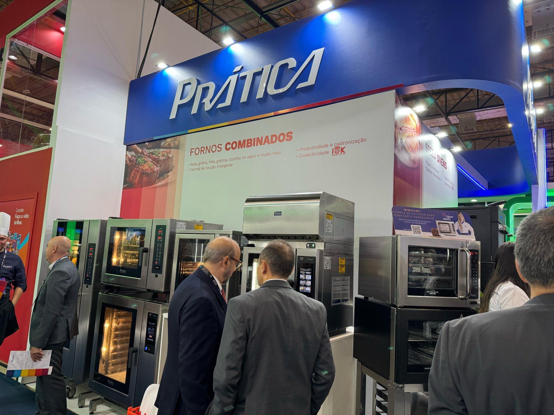 Um grupo de pessoas está em frente a uma exposição de fornos.