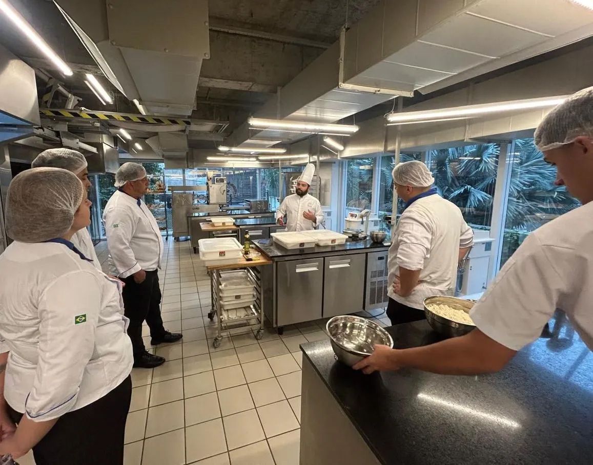 Um grupo de chefs estão em uma cozinha conversando entre si