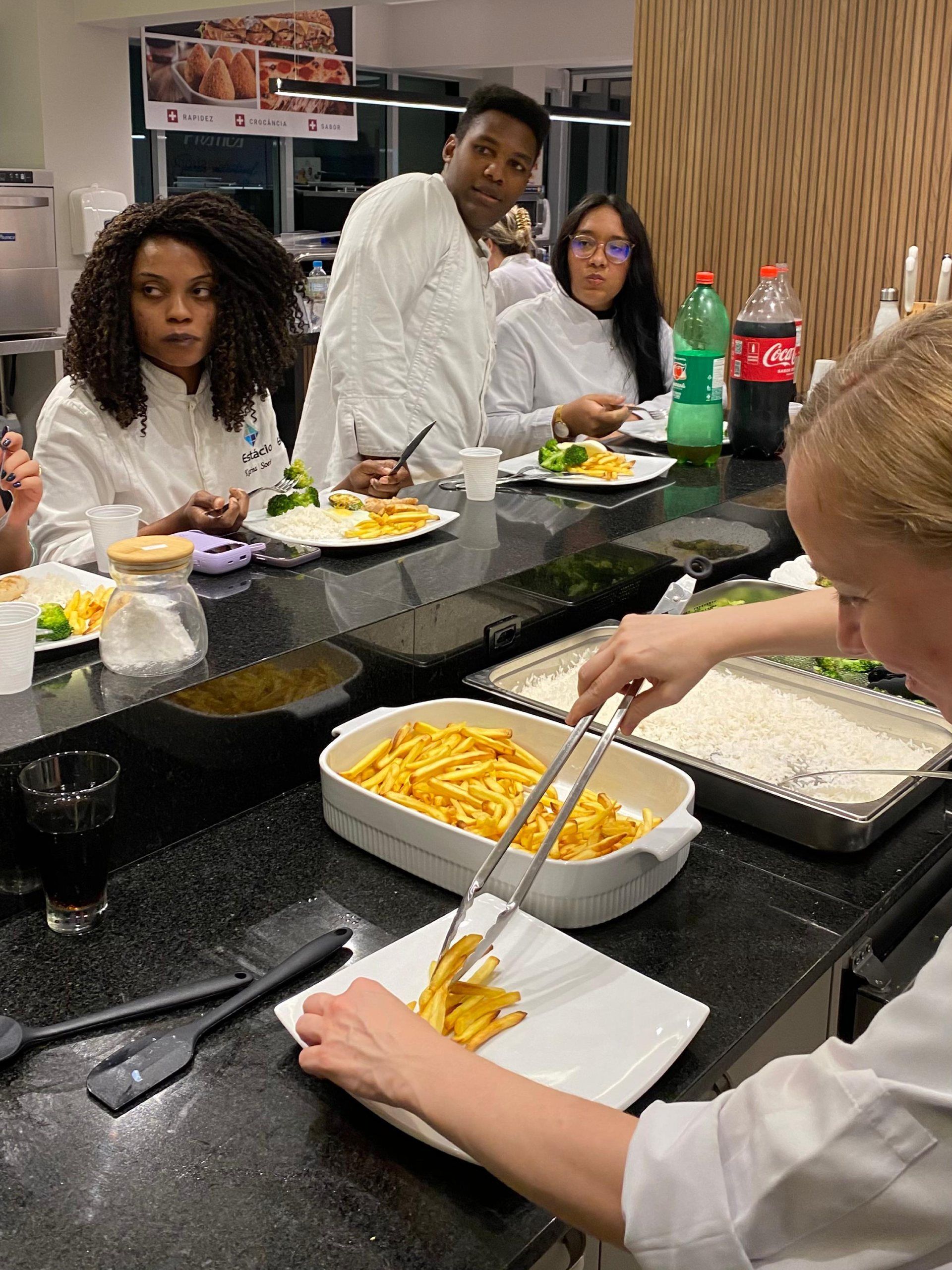 Um grupo de pessoas está sentado à mesa comendo.