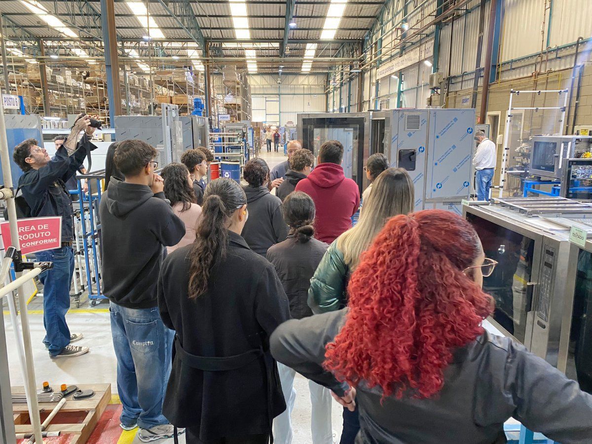 Um grupo de pessoas está em um armazém olhando para uma máquina.