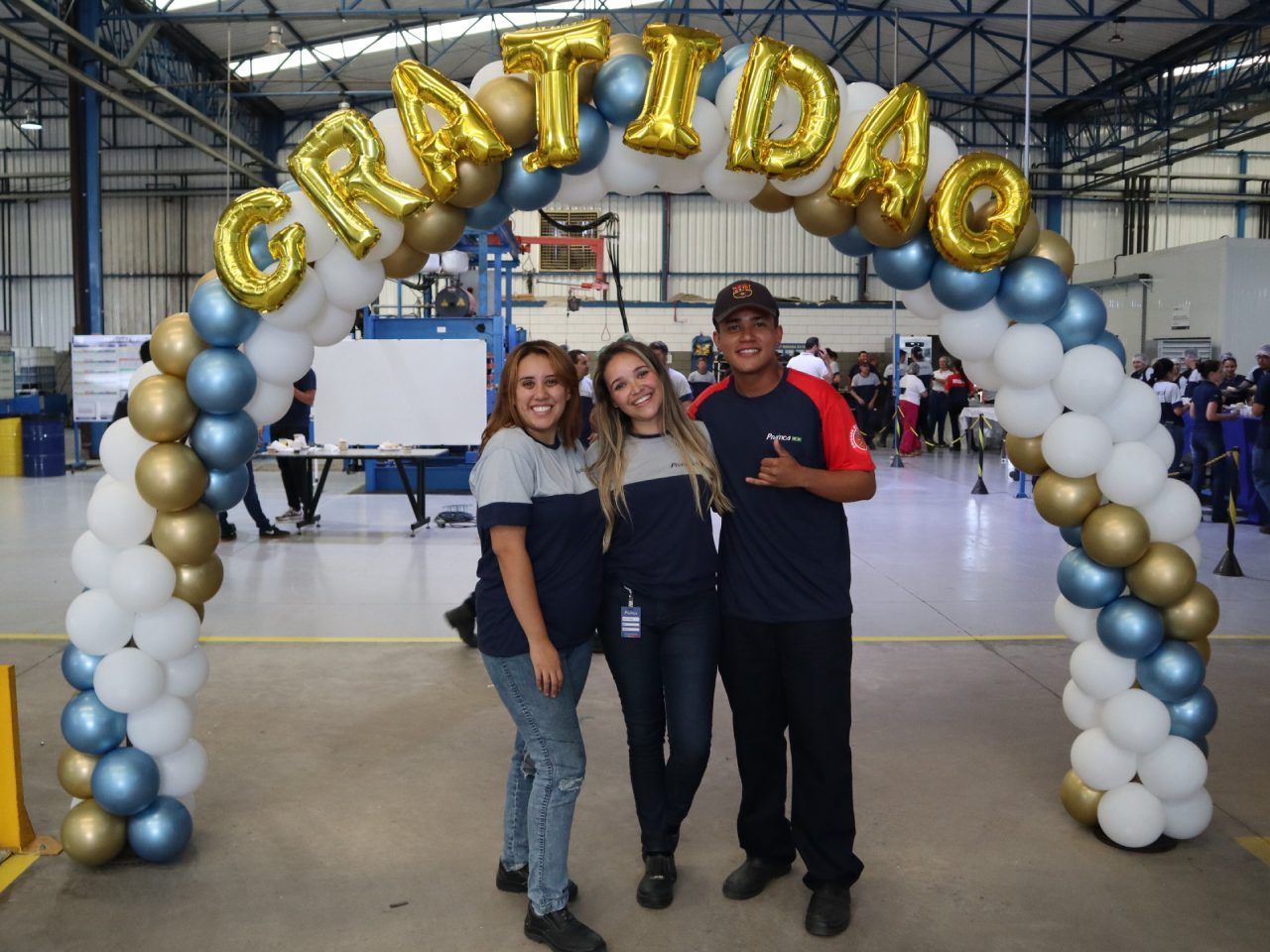 Um grupo de pessoas em pé sob um arco de balões que diz gratidao