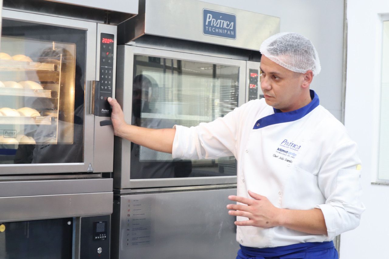Um homem está parado em frente a um forno em uma cozinha.