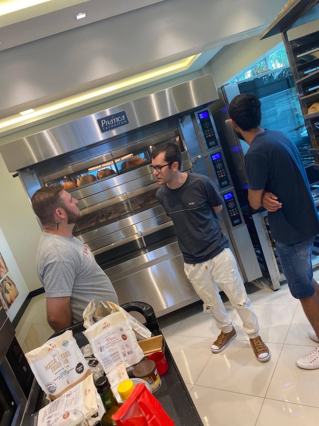 Um grupo de homens está em frente a um forno em uma padaria.