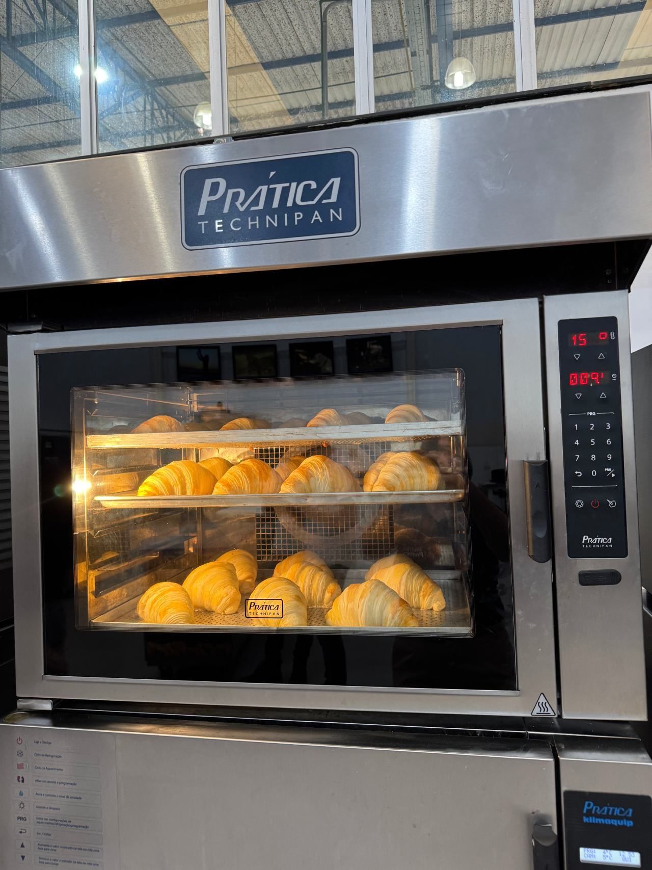 Croissants estão sendo assados em um forno de aço inoxidável.