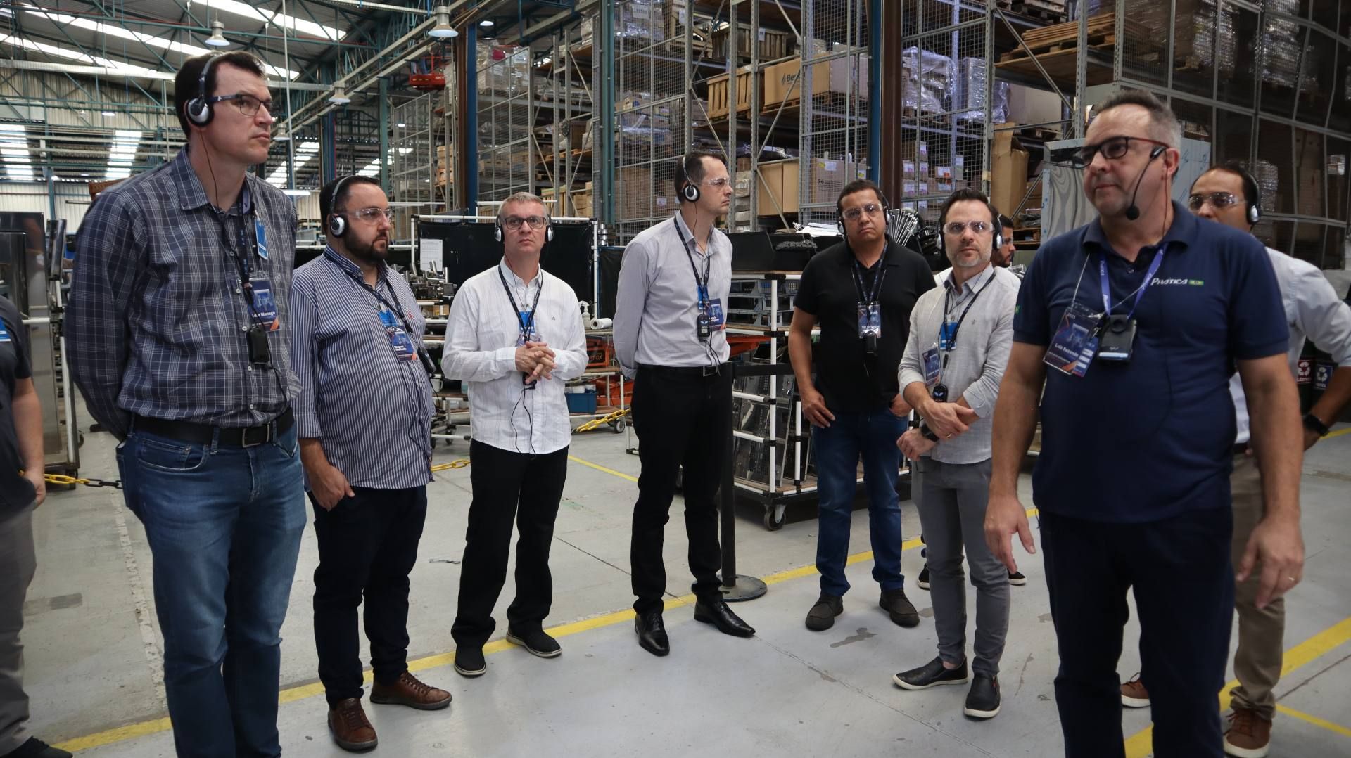 Um grupo de homens está em um armazém conversando entre si.