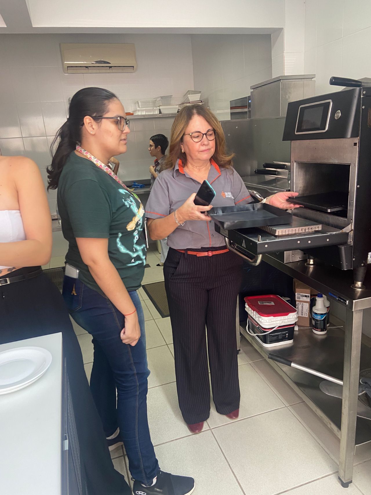 Um grupo de mulheres está em uma cozinha conversando entre si.