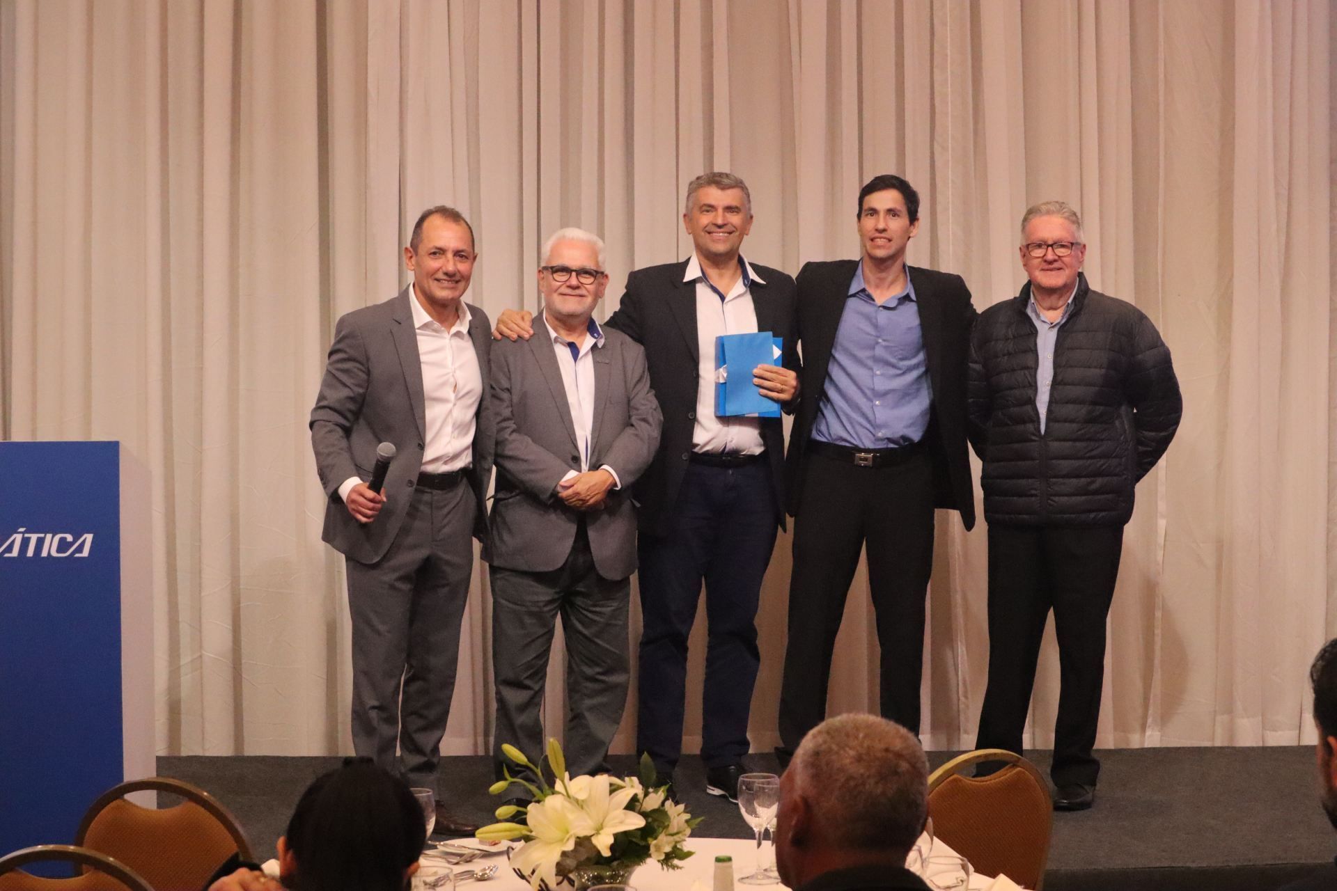 Um grupo de homens estão de pé, um ao lado do outro, em um palco.