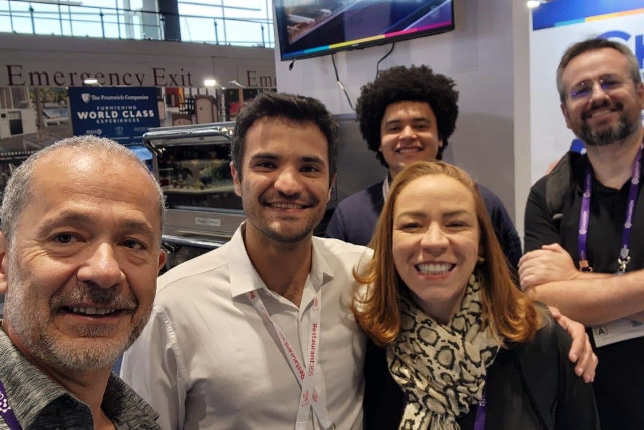 Um grupo de pessoas posando para uma foto em frente a uma placa que diz saída de emergência