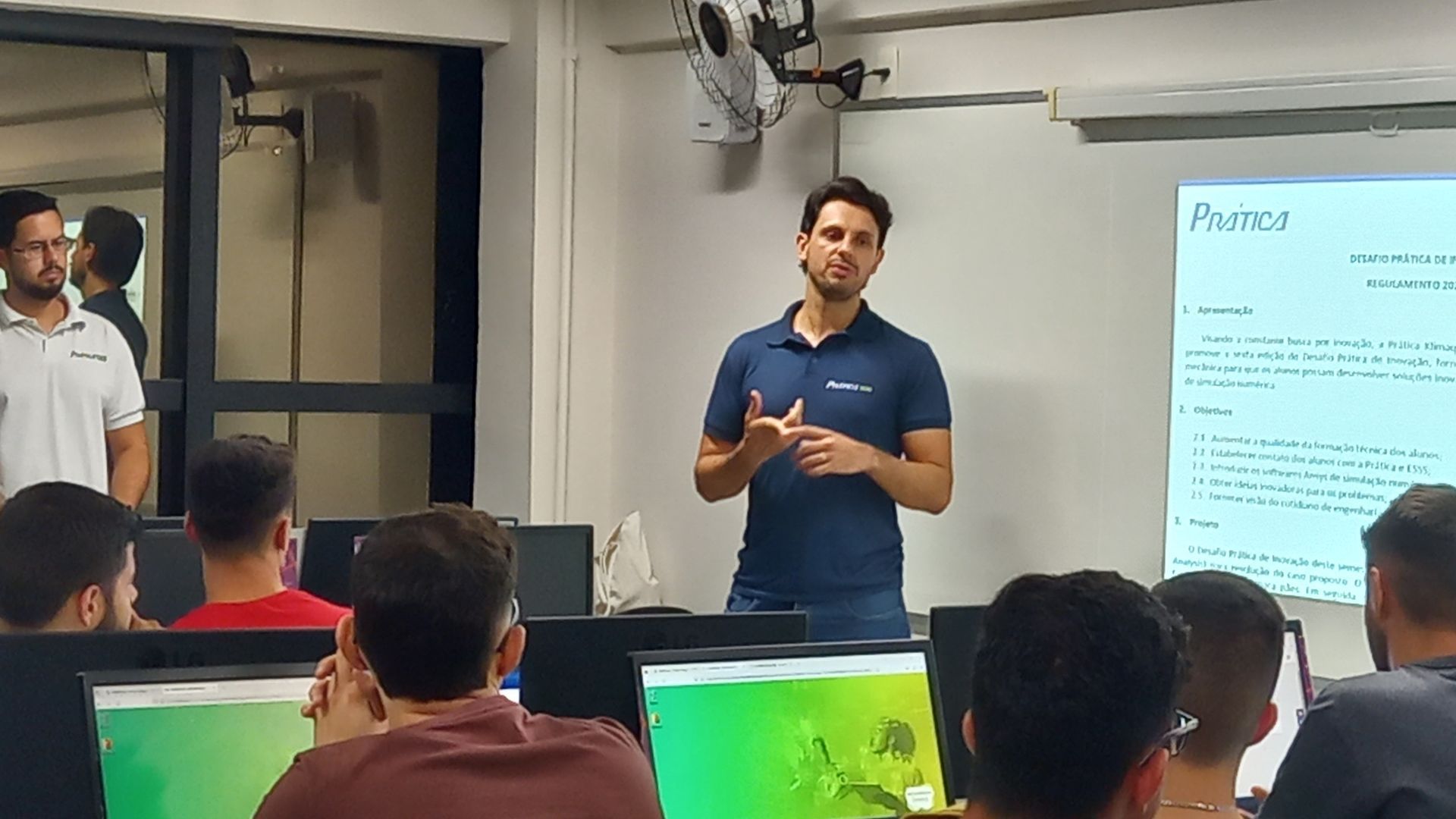 Um homem está fazendo uma apresentação para um grupo de pessoas em uma sala de aula.