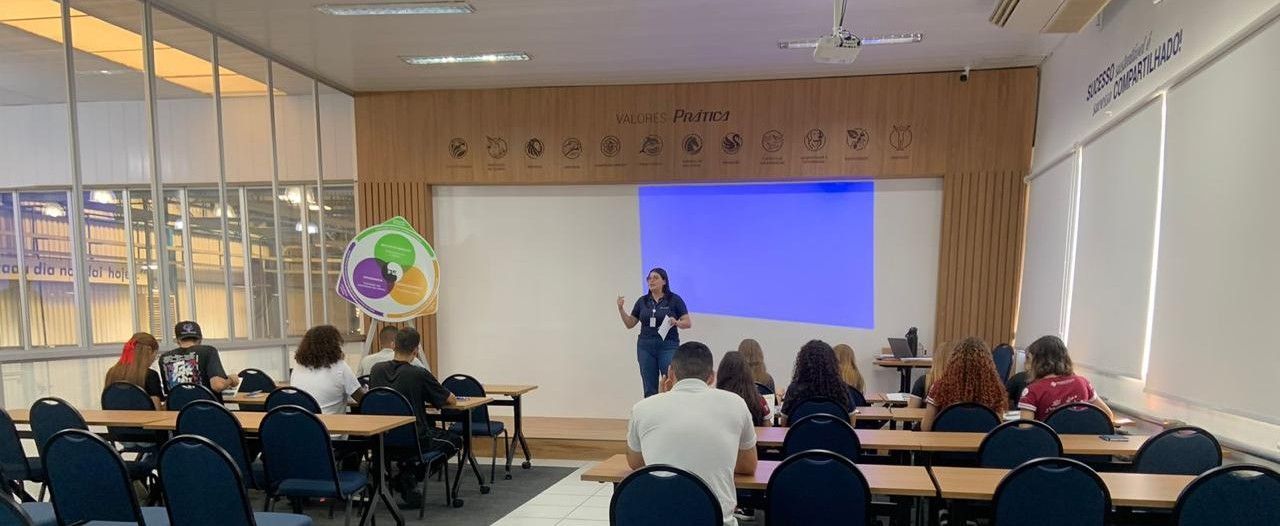 Uma mulher está fazendo uma apresentação para um grupo de pessoas em uma sala de aula.