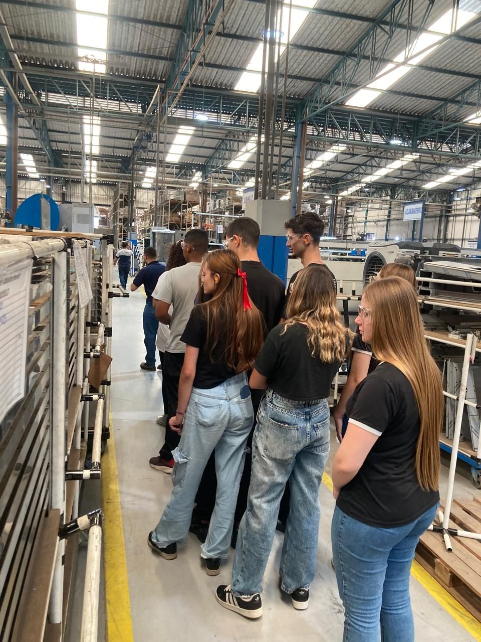 Um grupo de pessoas está em um armazém olhando para alguma coisa.