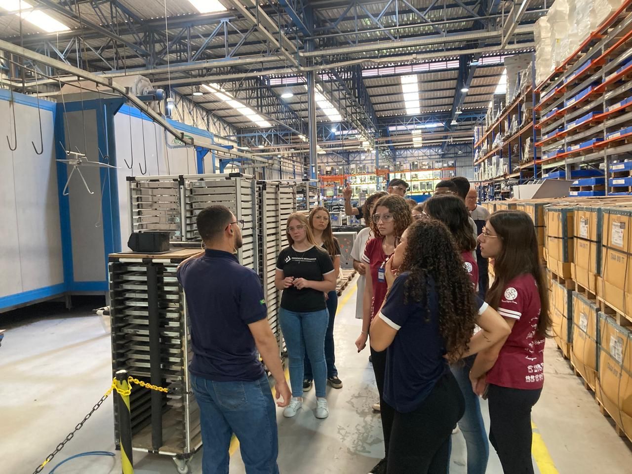 Um grupo de pessoas está em um armazém conversando com um homem.