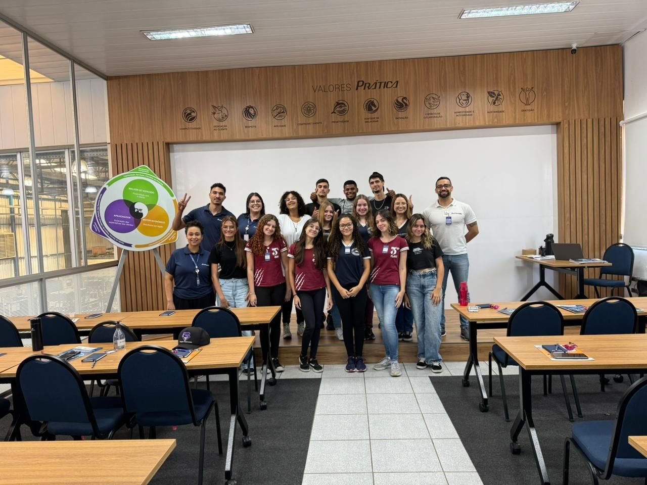 Um grupo de pessoas está posando para uma foto em uma sala de aula.