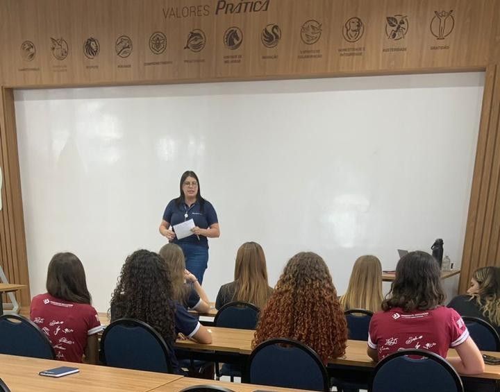 Uma mulher está fazendo uma apresentação para um grupo de pessoas em uma sala de aula.