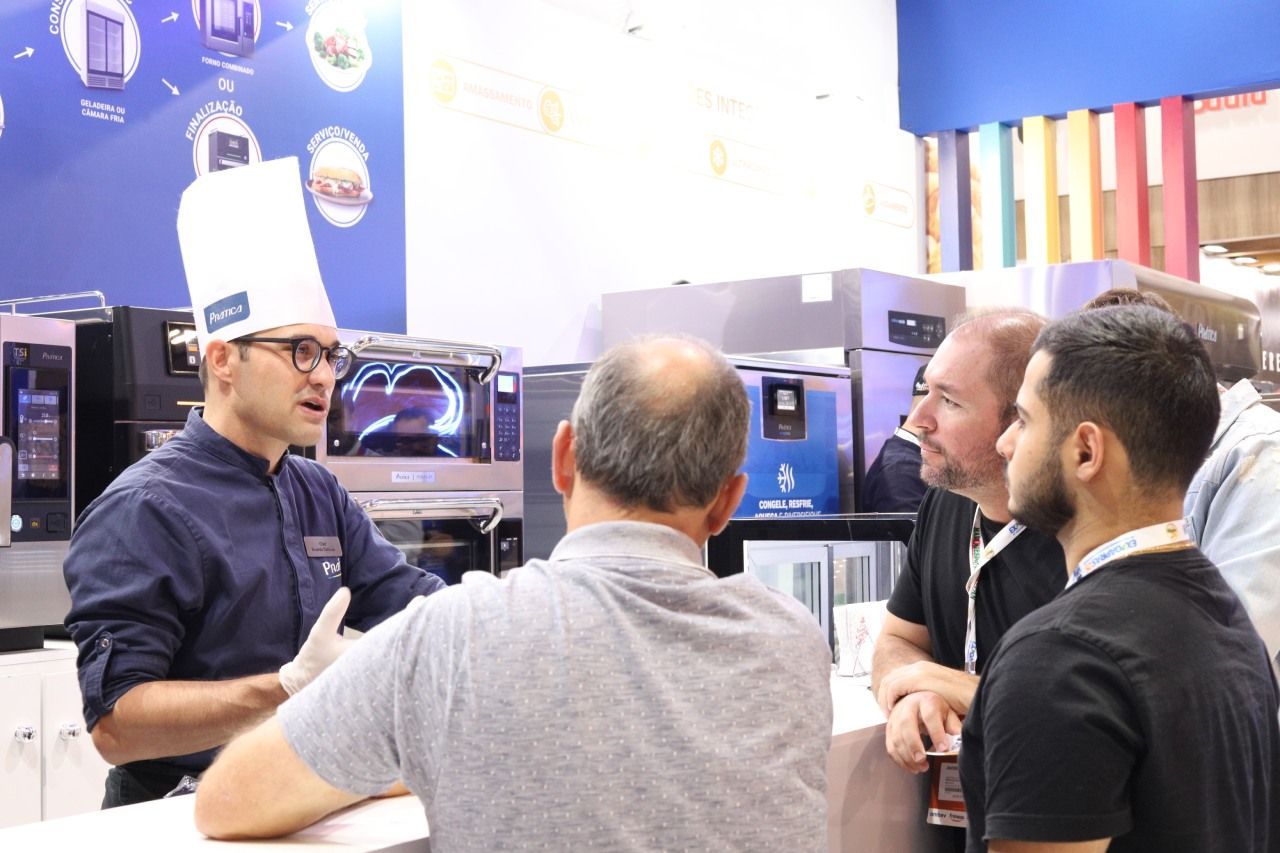 Um homem com chapéu de chef está conversando com um grupo de homens.