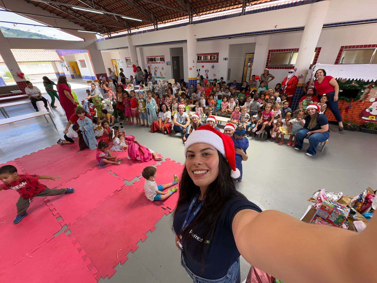 Uma mulher com um chapéu de Papai Noel está tirando uma selfie com um grupo de crianças.