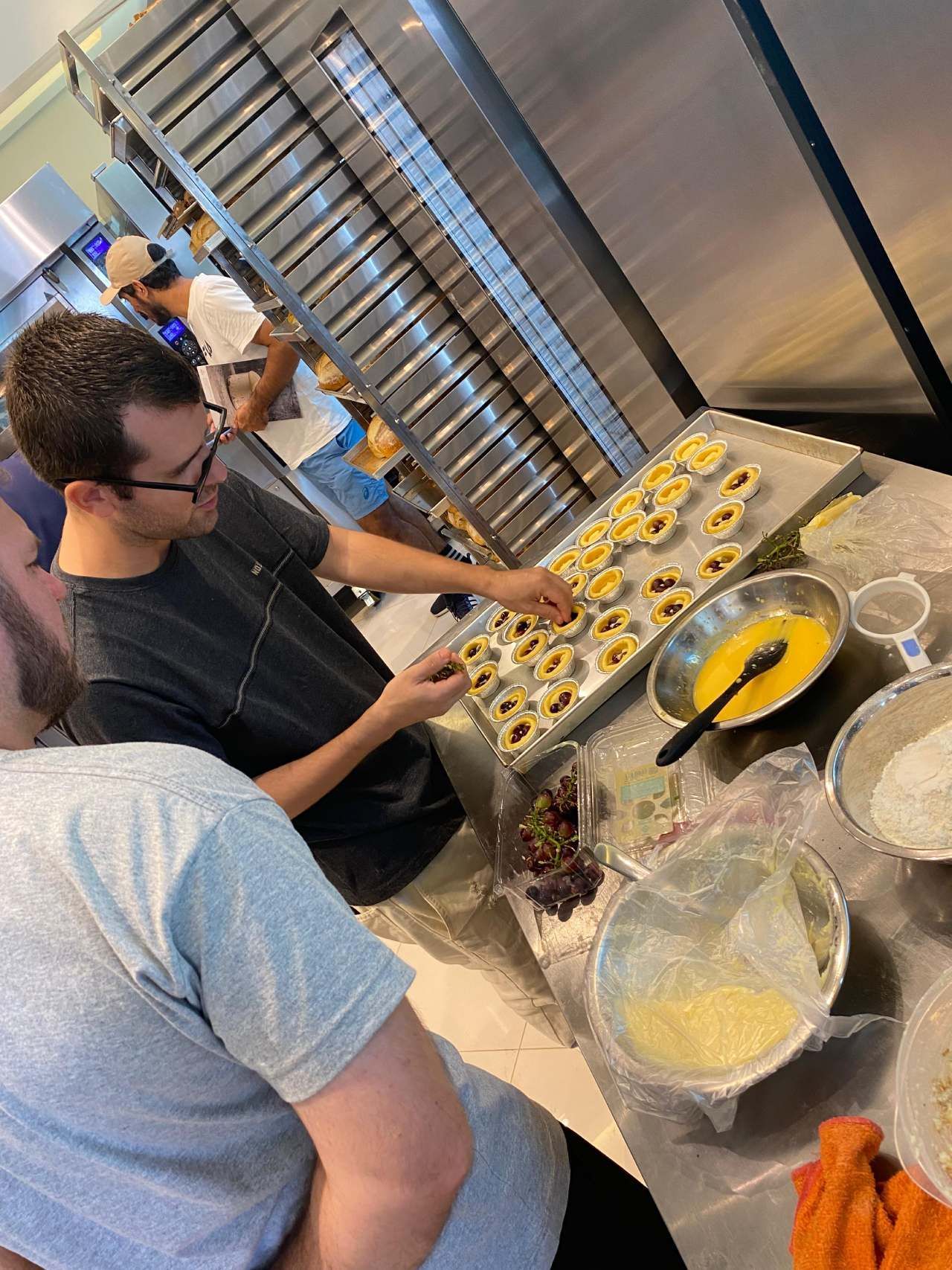 Um homem está preparando comida em uma cozinha com outras pessoas