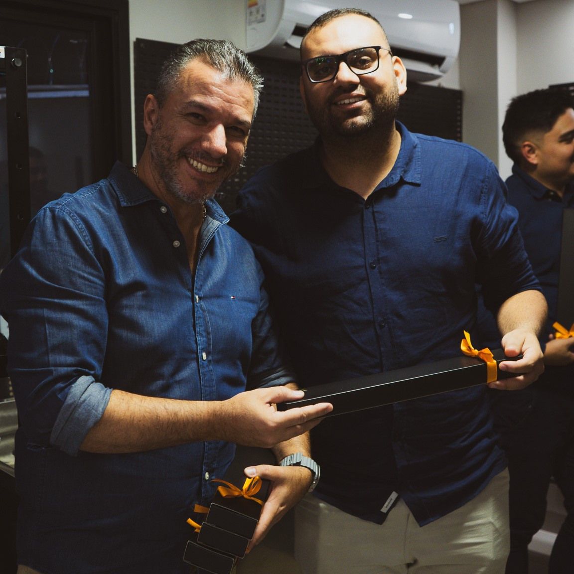 Dois homens estão posando para uma foto e um deles está segurando um violão