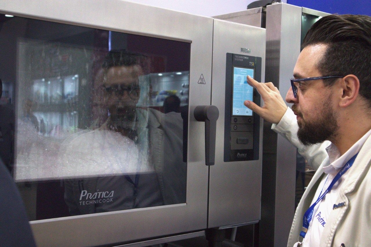 Um homem está apontando para a tela de um forno de convecção.