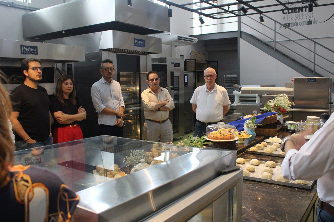 Um grupo de pessoas está em uma cozinha olhando para a comida