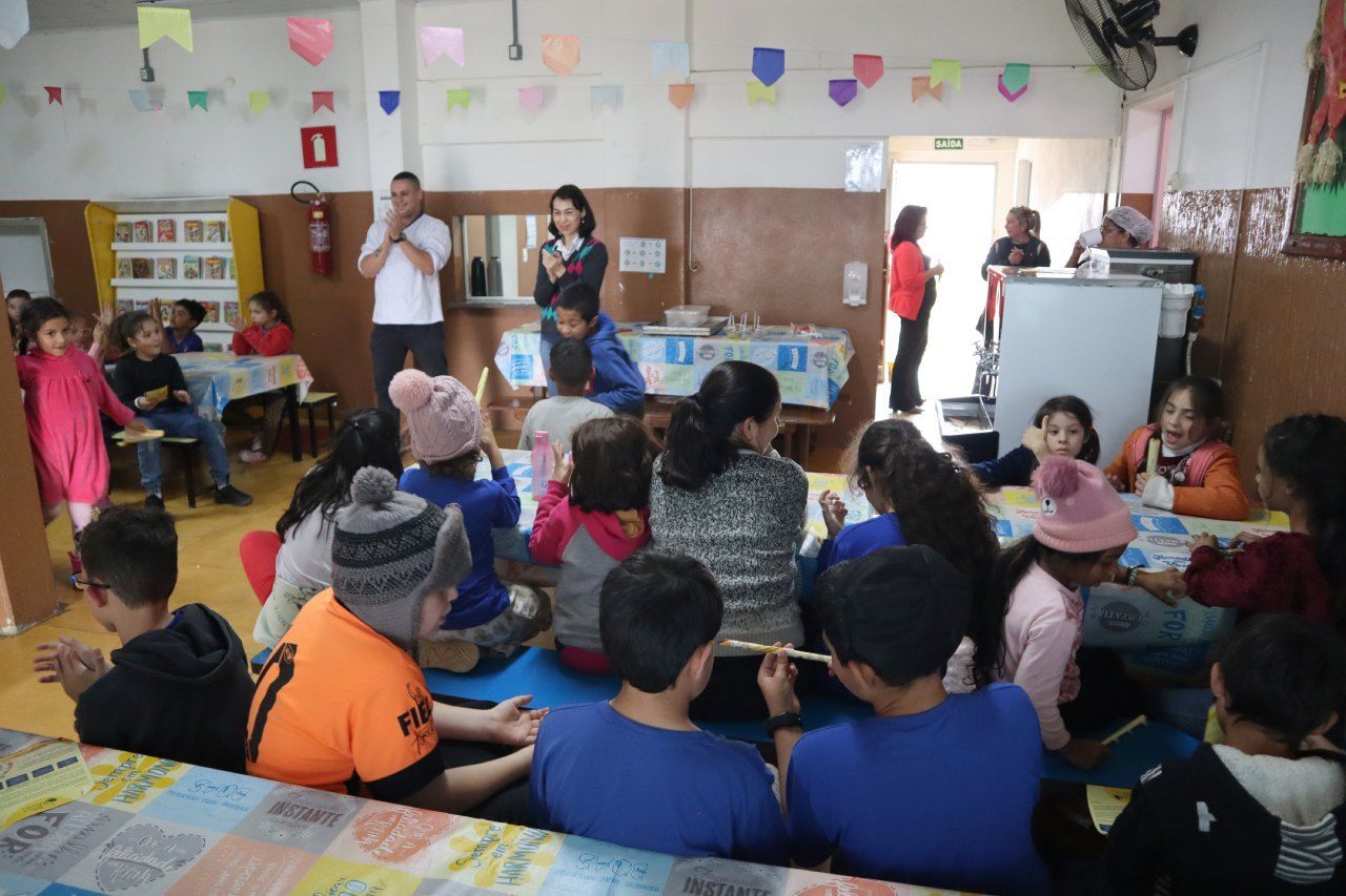 Um grupo de crianças está sentado no chão de uma sala de aula.