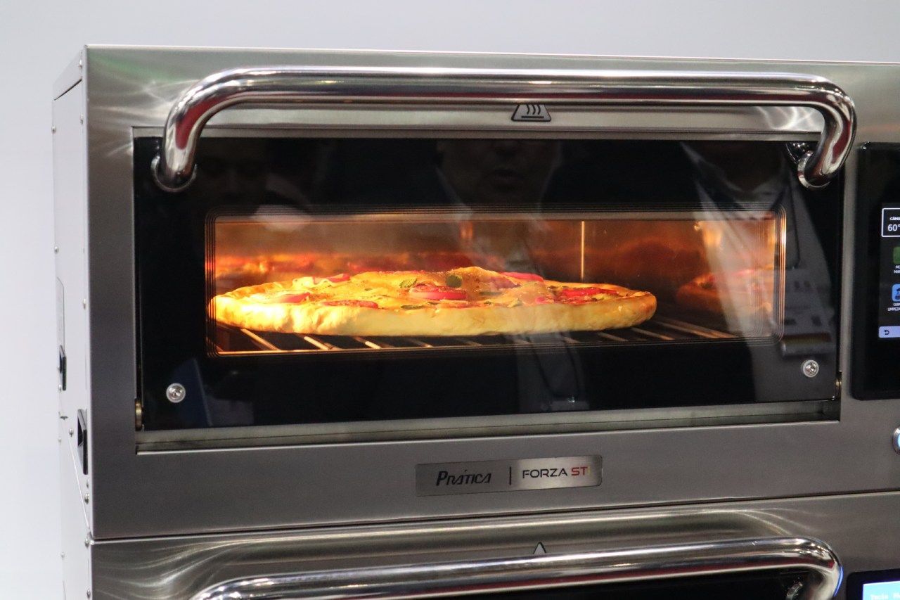 Uma pizza está assando em um forno de aço inoxidável.