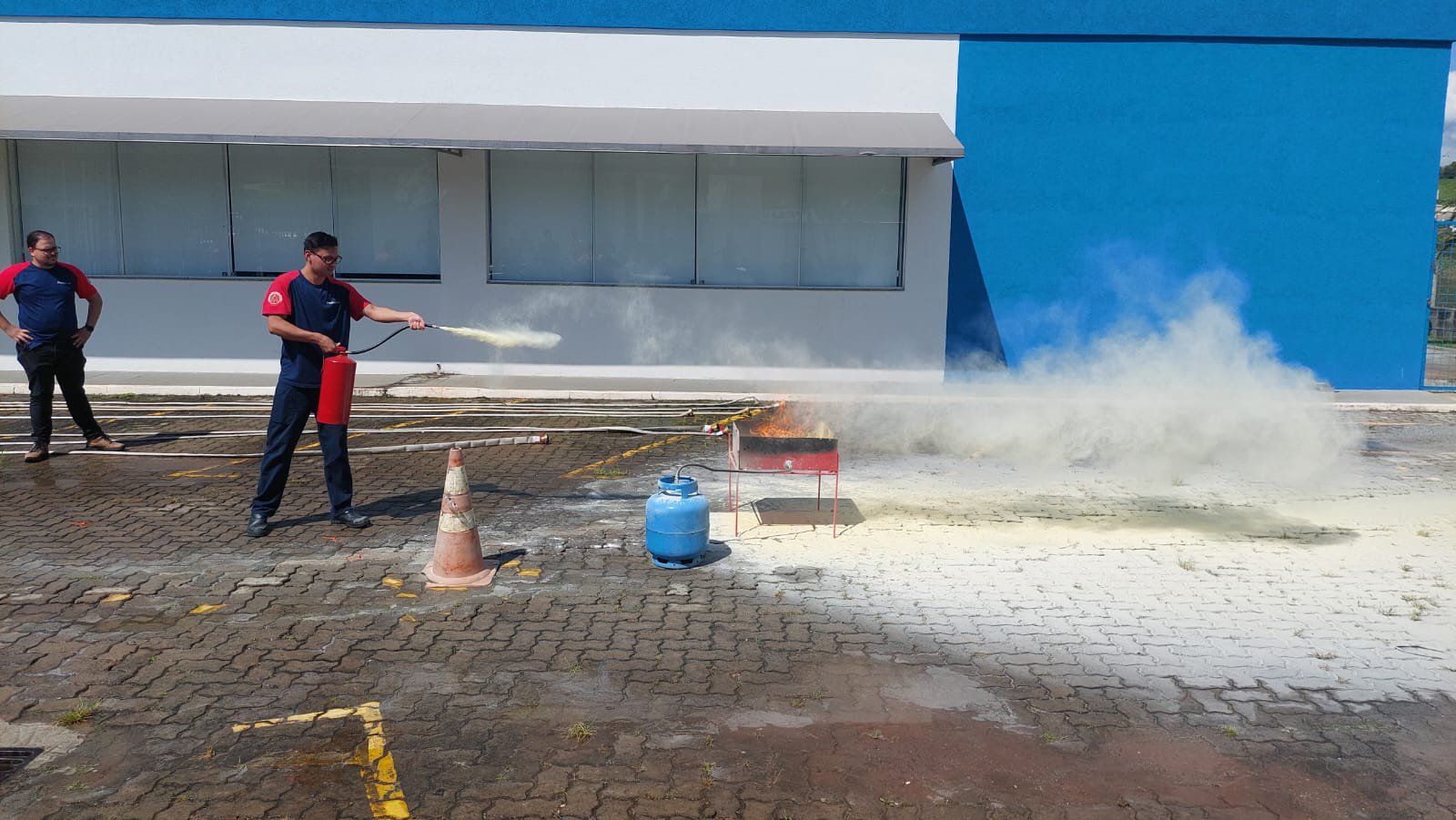 Um homem está usando um extintor de incêndio para apagar um incêndio em um estacionamento.