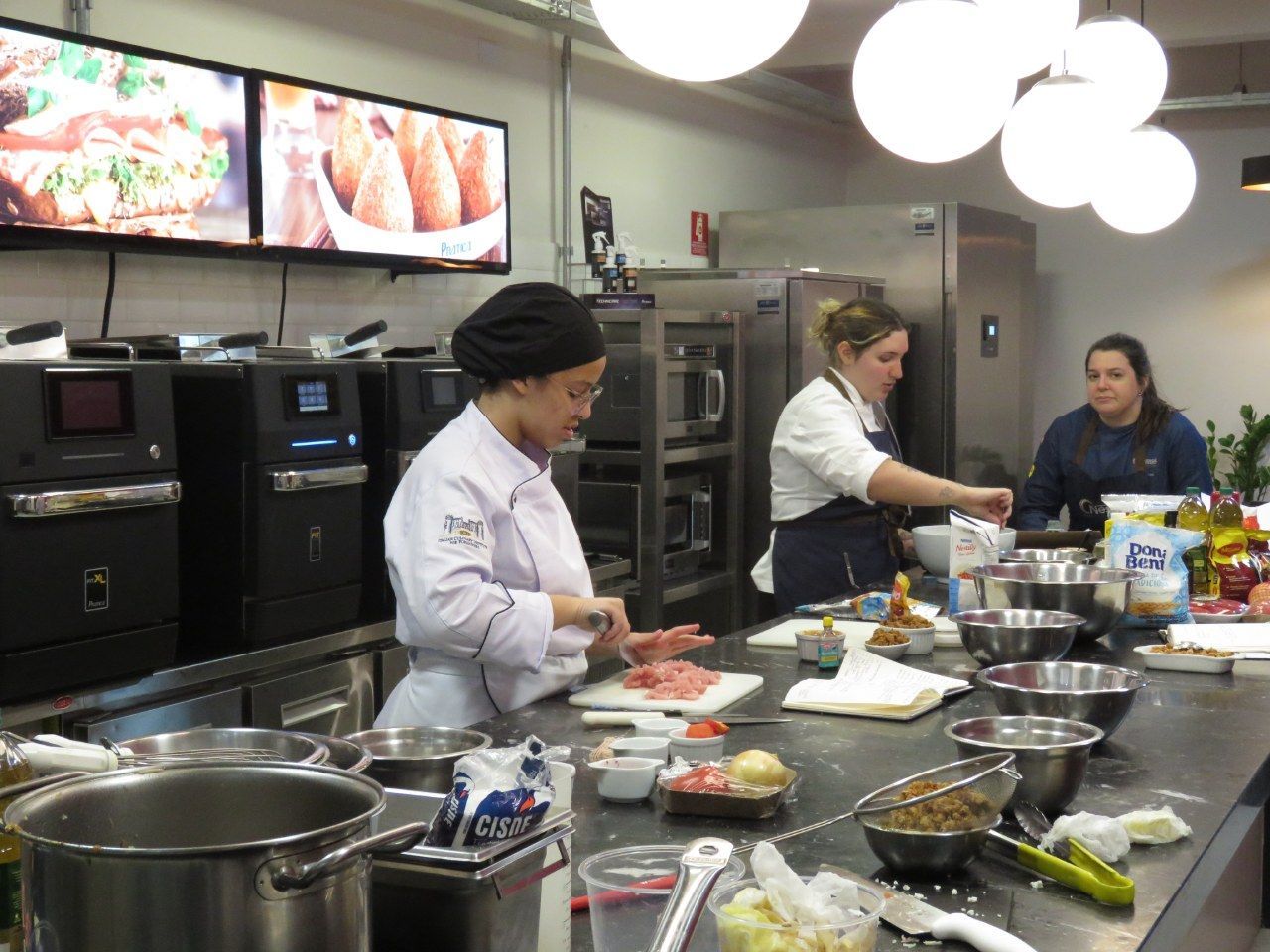 Um grupo de mulheres está preparando comida em uma cozinha.