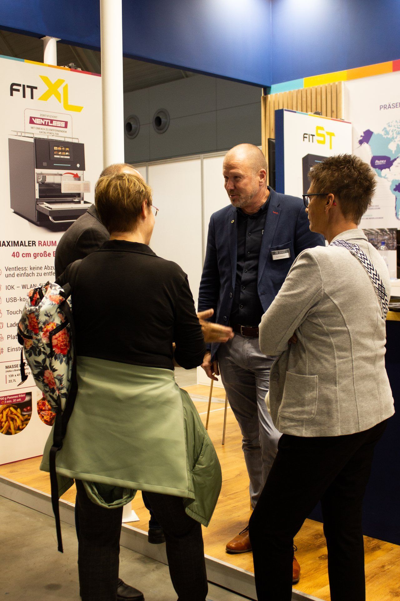 Um grupo de pessoas está em uma sala conversando entre si.