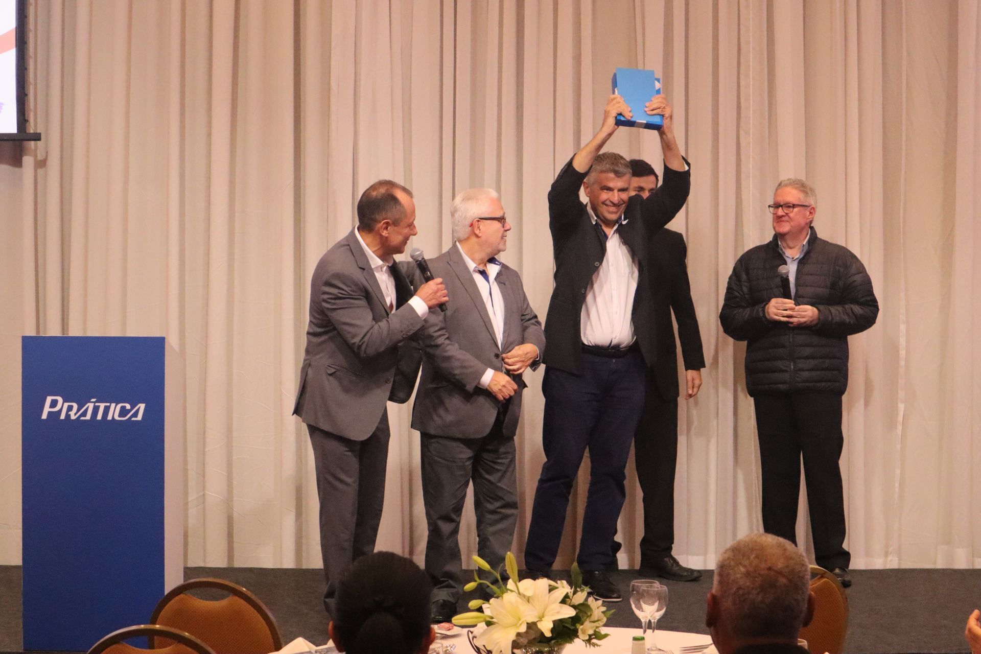 Um grupo de homens está em um palco segurando um troféu.