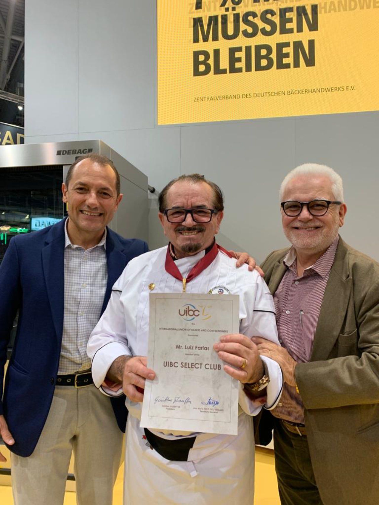 Três homens estão posando para uma foto e um deles está segurando um certificado.