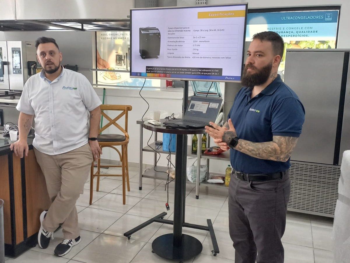 Dois homens estão em pé em frente a uma tela de projetor em uma cozinha.