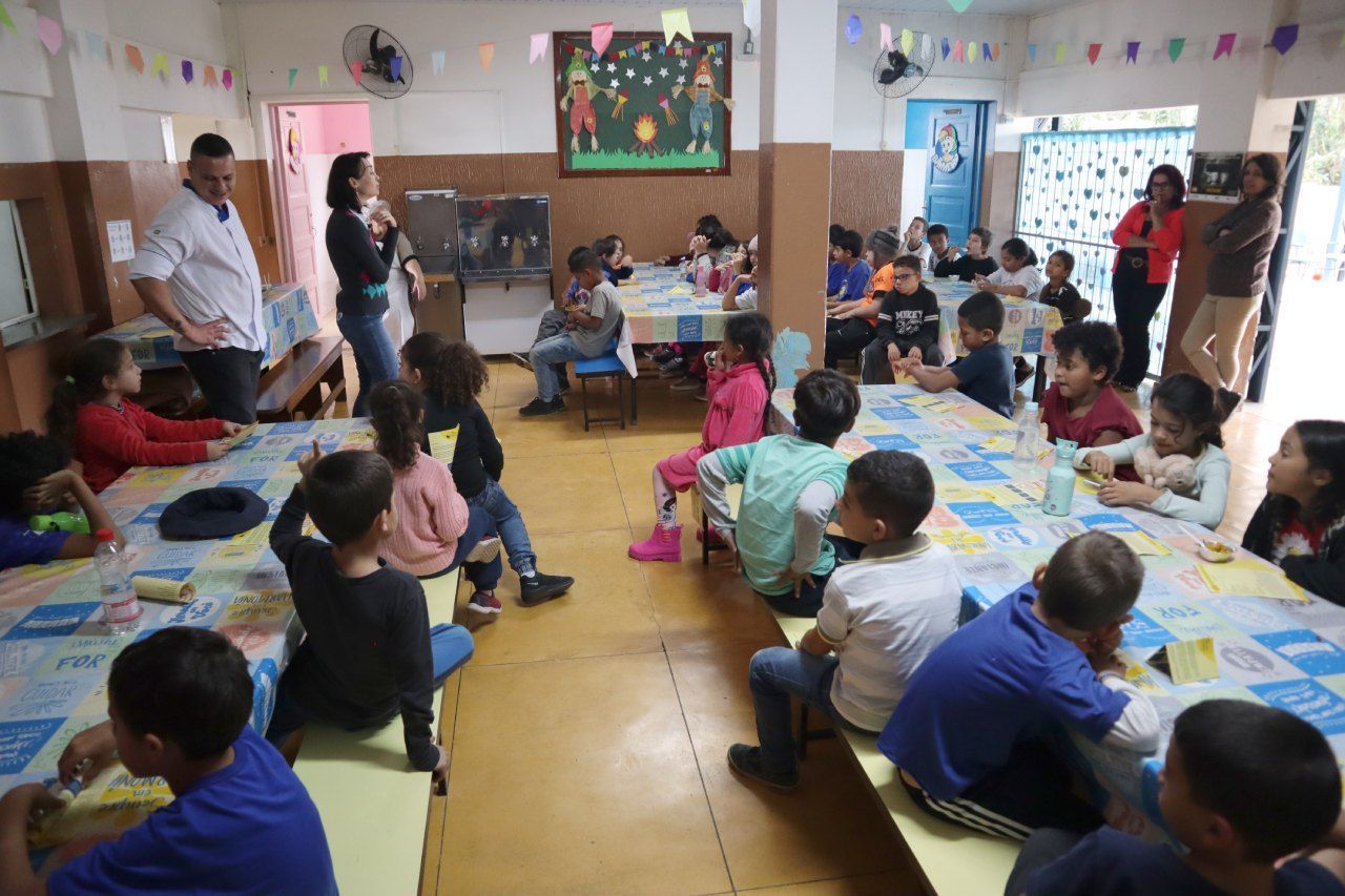 Um grupo de crianças está sentado em mesas em uma sala
