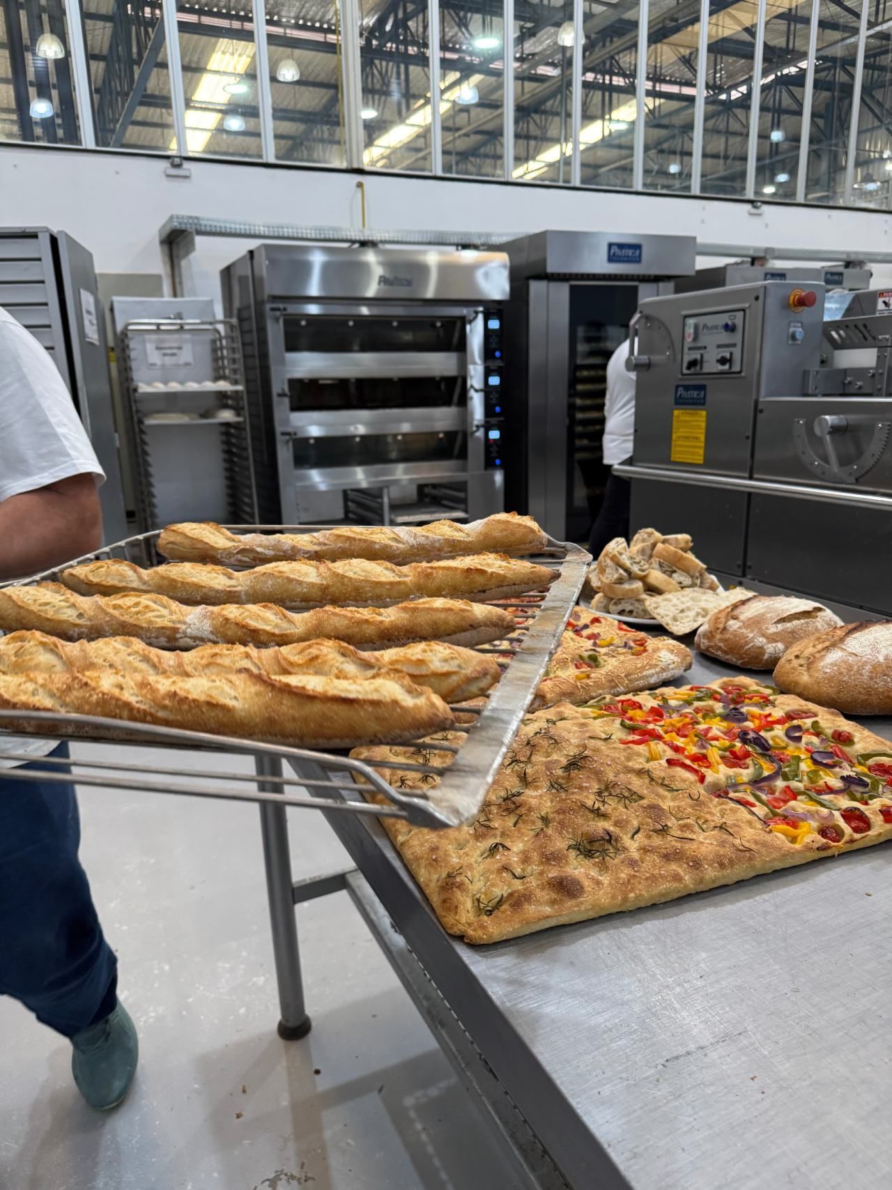 Uma pessoa está segurando uma bandeja de pão em uma padaria.