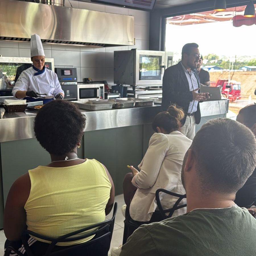 Um grupo de pessoas sentadas em frente a um chef em uma cozinha