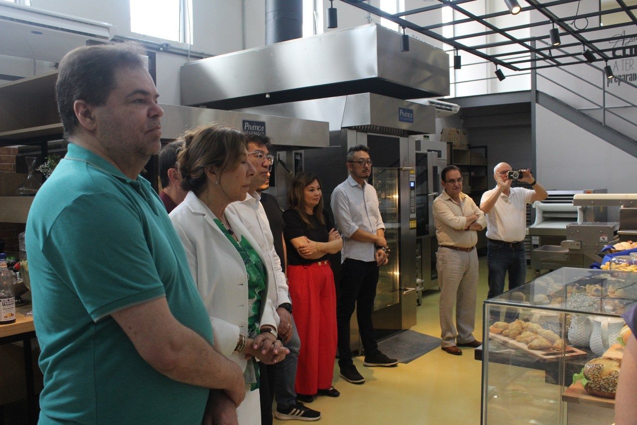 Um grupo de pessoas está em uma cozinha olhando para uma vitrine.