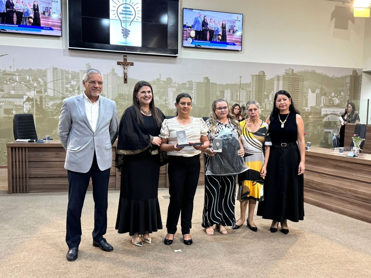 Um grupo de mulheres estão de pé, uma ao lado da outra, em uma sala.