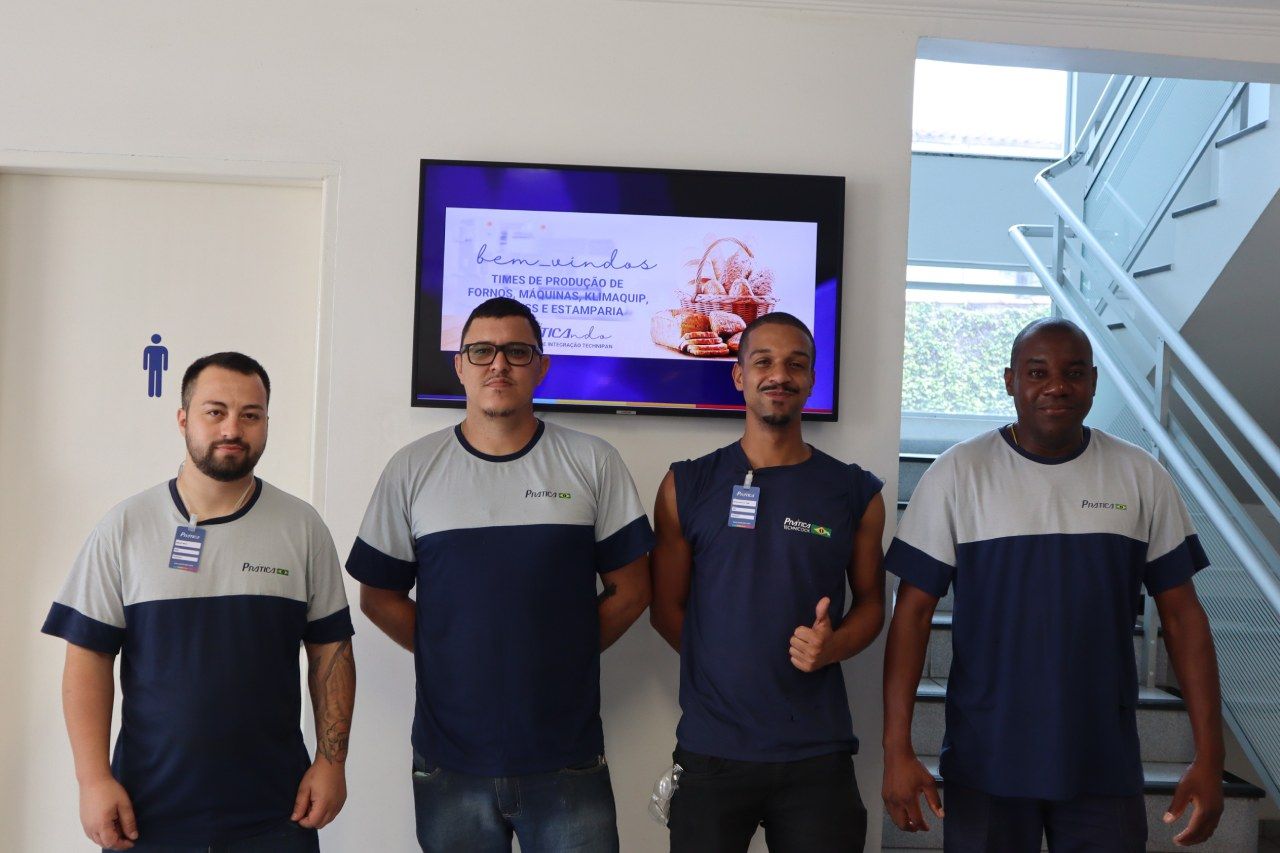 Um grupo de homens em pé na frente de uma TV de tela plana