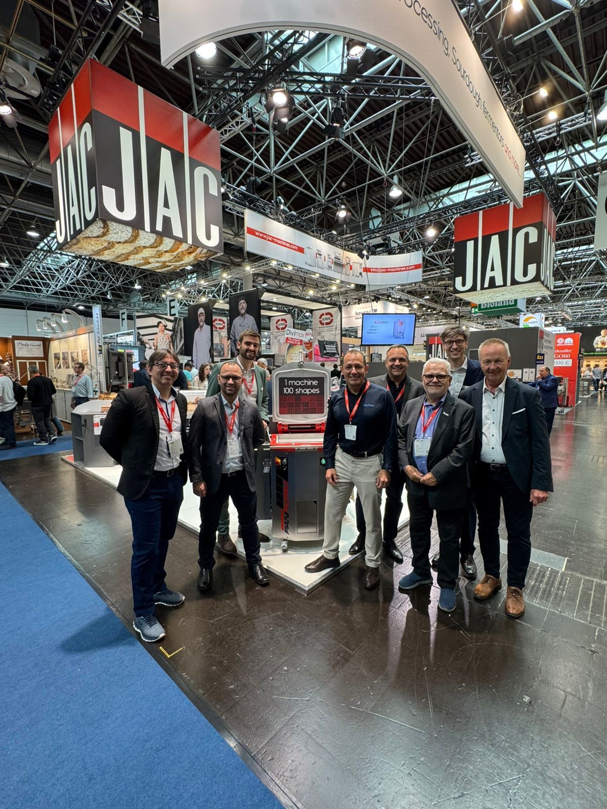 Um grupo de homens está parado em frente a uma placa que diz jac.