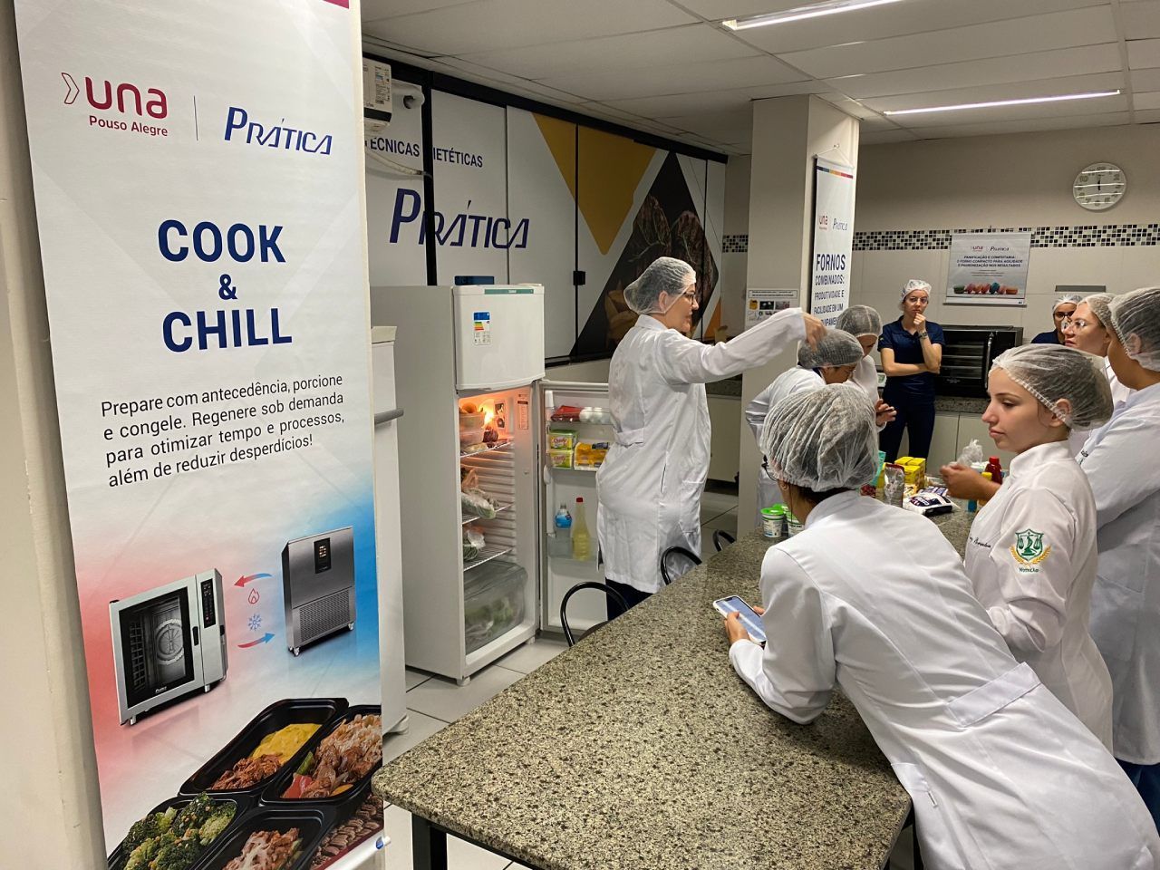 Um grupo de pessoas está em pé ao redor de uma mesa em frente a uma placa que diz cozinhe e relaxe.