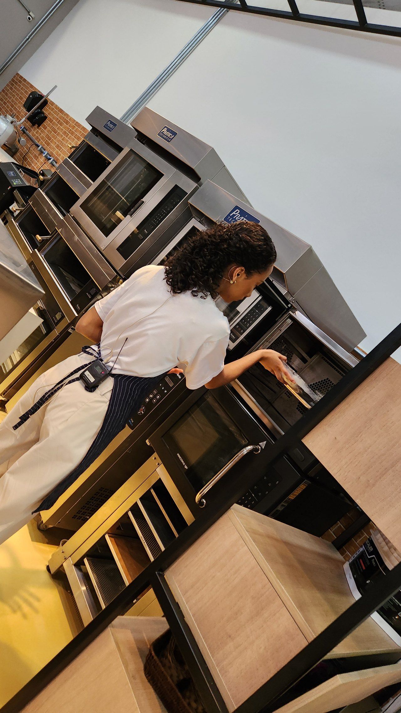 Uma mulher está parada em frente a um forno na cozinha.