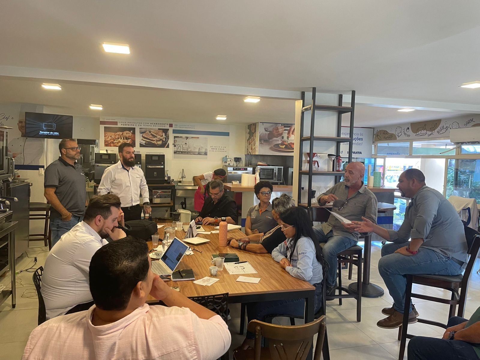 Um grupo de pessoas está sentado ao redor de uma mesa em um restaurante.